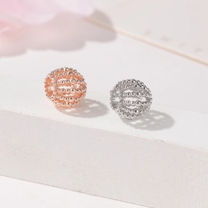 Primer plano de cuentas de esfera hueca en oro rosa y plata con superficie de metal texturizada