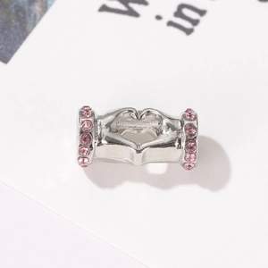 Détail macro du charm geste du cœur en argent avec cristaux roses pour bijoux de bracelet