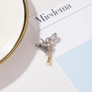 Detailed view of silver graduation cap charm with gold bell and graduation engraving