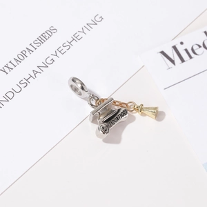 Close-up of graduation charm with diploma and mortarboard cap in silver and gold