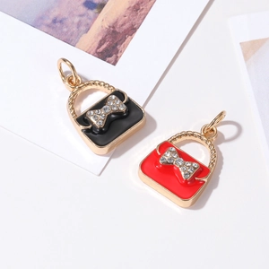 Mini handbag charms with gold handles and rhinestone bows in black and red enamel