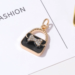Macro view of black enamel handbag charm with rhinestone bow and gold twisted handle