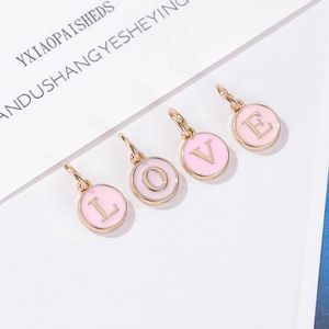 Primer plano de dijes LOVE en esmalte rosa con bordes dorados para crear joyas