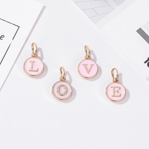 Detalle de dijes LOVE en esmalte rosa con baño de oro para creación de joyería DIY