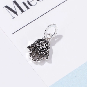 Detalle macro de colgante Mano de Fátima en plata antigua con ojo turco grabado