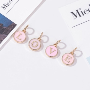 Vista detallada de cuatro colgantes LOVE de esmalte rosa y oro para joyería DIY