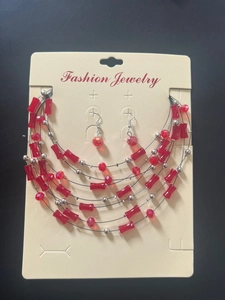 Detail view of multi-layer beaded necklace and earrings set on jewelry card