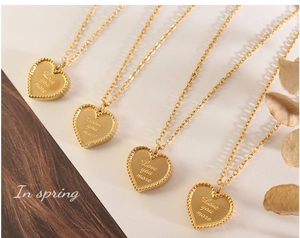 Détail de quatre colliers cœur dorés avec gravure Love you more et bordure perlée