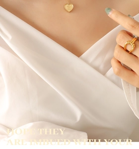 Détail du pendentif cœur doré gravé Love you more et bague épaisse sur mannequin