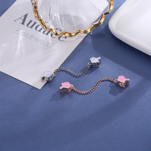 Dettaglio di ciondoli a forma di mano rosa e bianca con catene su uno sfondo blu scuro