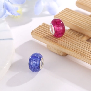 Macro view of crackle glaze resin charm beads with silver metal cores on a floral background