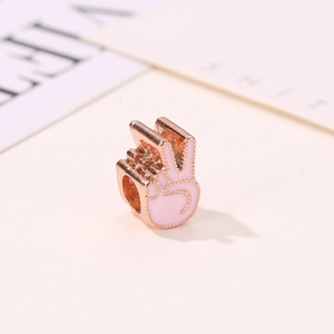 Détail macro d'un charm geste de victoire en or rose et émail rose pour bracelets DIY