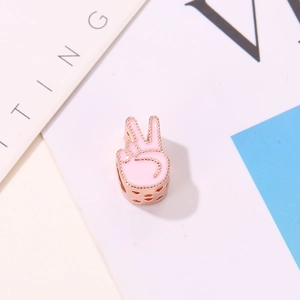 Vue macro du charm V en émail rose avec détails de cœur évidés en or rose pour bracelets