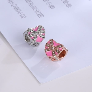 Close-up of pink enamel heart charms with bow and zircon inlay for DIY jewelry