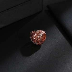 Vista macro de un abalorio hueco en oro rosa con diseño de filigrana para joyería DIY