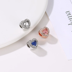 Macro shot of heart-shaped charm beads with sparkling crystals in silver and rose gold