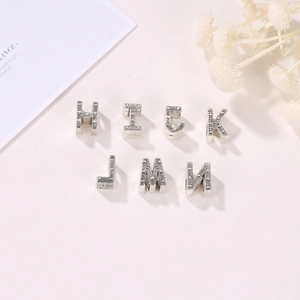Detalle macro de cuentas de letras de metal plateado vintage para joyas y pulseras DIY