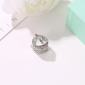 Charm a cuore in argento con zirconi rosa e viola su sfondo di scatola regalo