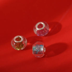 Macro detail of three handmade transparent glass beads with colorful glitter and metal cores