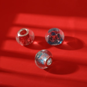 Detailed close-up of three sparkling glass beads with colorful glitter and metal cores