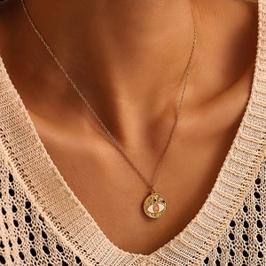 Gouden Evil Eye ketting met roze zirkoon hanger gedragen op witte gebreide kleding