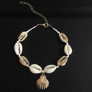 Close-up of handmade shell bracelet with golden shell pendant on a black surface
