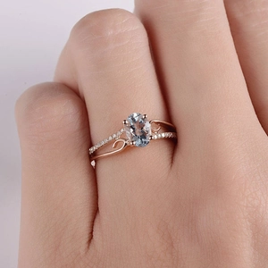 Elegante anello in oro rosa con pietra blu ovale e fascia incrociata con diamanti luminosi