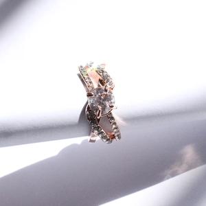 Bague croisée en or rose avec un zircon rond central et des pierres pavées sur les côtés