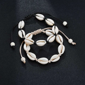 Detail of natural white shell bracelets with adjustable cords on a black surface