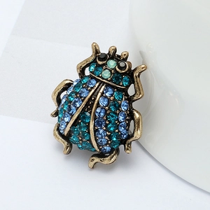 Broche scarabée vintage ornée de strass bleus avec une finition en or antique raffinée