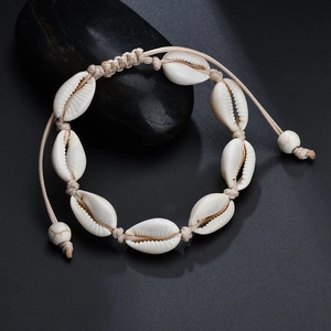 Detailed view of handmade seashell bracelet with adjustable woven rope on a black stone