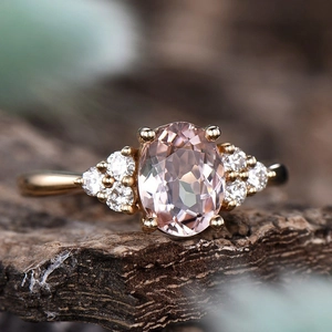 Eleganter roségoldener Ring mit ovalem rosa Stein und Diamantclustern auf Baumrinde