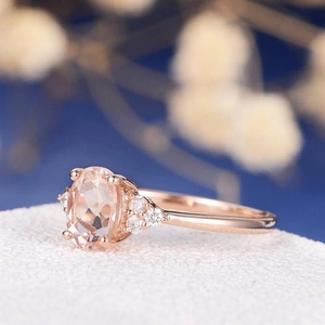 Makroansicht eines Roségold-Rings mit ovalem rosa Edelstein und seitlichen Diamanten