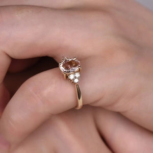 Eleganter Roségoldring mit ovalem rosa Zirkonstein und Diamantclustern an der Hand