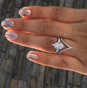 Close-up of a marquise-cut bridal ring set with a V-shaped pavé band on a dark background