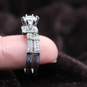 Nahaufnahme eines zweiteiligen silbernen Ehering-Sets mit einem klassischen Sechs-Klauen-Ring