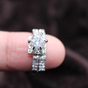 Makroaufnahme von Silber-Ehering-Set mit rundem Hauptstein und Pavé-Verzierung