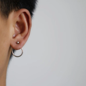 Conjunto de pendientes de esfera plateada pulida y aro fino lucidos en un perfil lateral