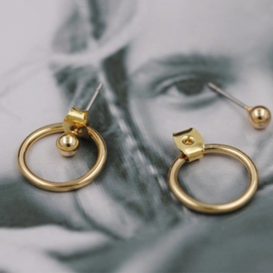 Detalle macro de pendientes geométricos dorados desmontables con acabado de metal pulido