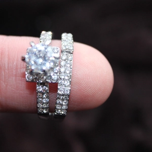 Makroaufnahme eines zweiteiligen Ehering-Sets mit quadratischem Diamanten und Silberband