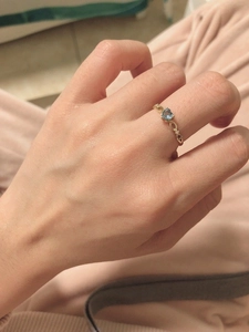 Primo piano anello con topazio blu a cuore con simbolo infinito e fascia dorata al dito
