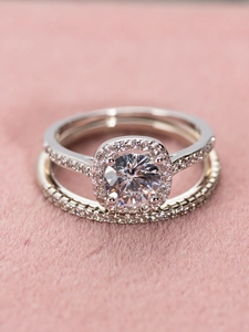Exquisito juego de dos anillos de cobre con diamante halo redondo y bandas con pavé