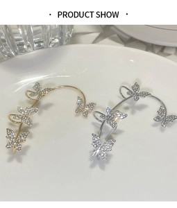Detailed view of silver and gold butterfly ear cuffs with sparkling rhinestones in a tray