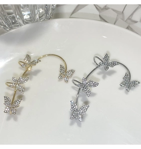 Detailed macro shot of gold and silver butterfly ear cuffs with sparkling crystals