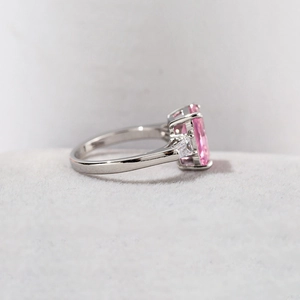 Elegant silver ring with a pink emerald-cut center stone and trapezoid side diamonds