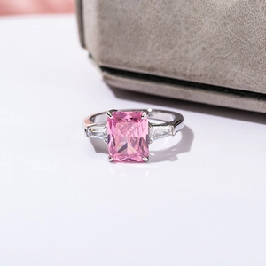 Close-up of a silver ring featuring a pink rectangular gemstone and side trapezoid stones