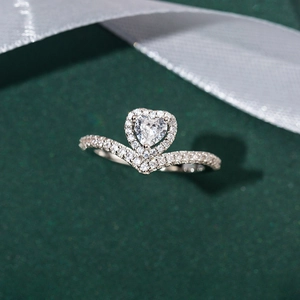Elegant V-shaped heart crown ring with sparkling zircons on a dark green background