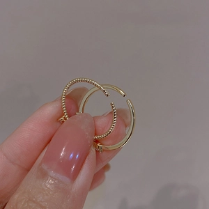 Dettaglio anello doppio dorato con trama a spirale intrecciata e finitura lucida