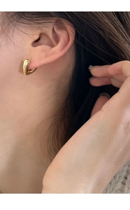 Gros plan d'une boucle d'oreille dorée en forme de V portée sur le lobe de l'oreille