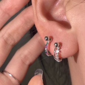 Close-up of 925 silver ear bone rings with colorful zircons and screw ball backings